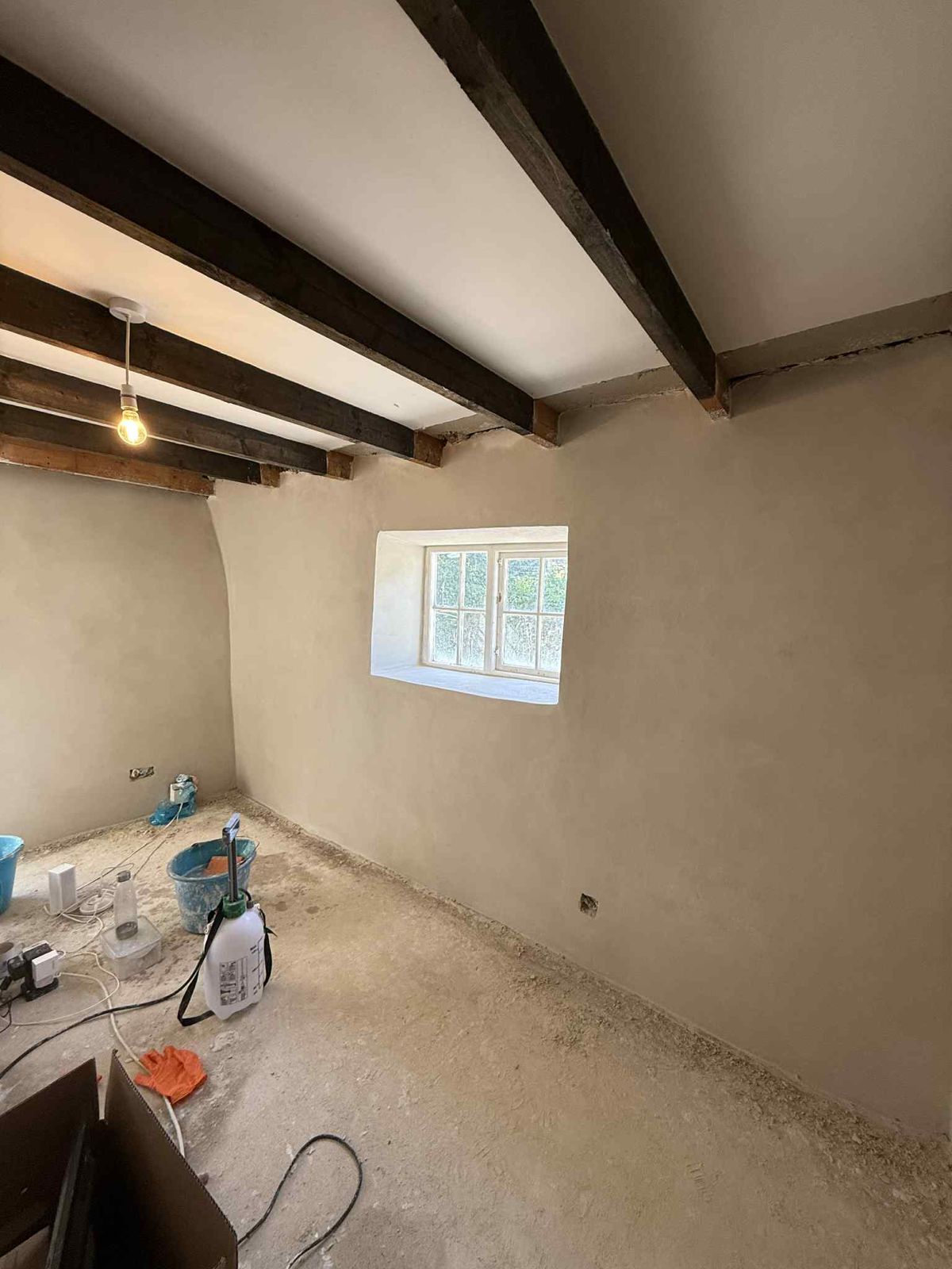 A beamed cottage room with freshly plastered lime walls