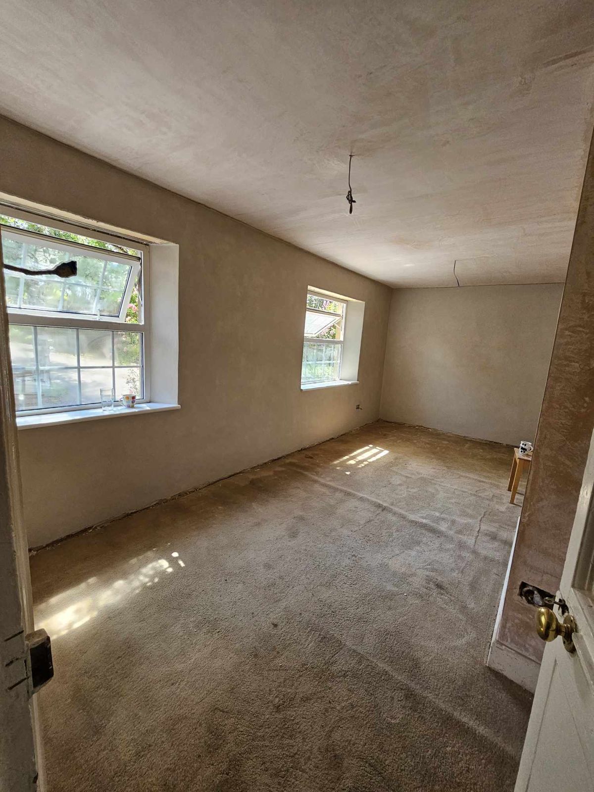 A bedroom freshly plastered, with two windows