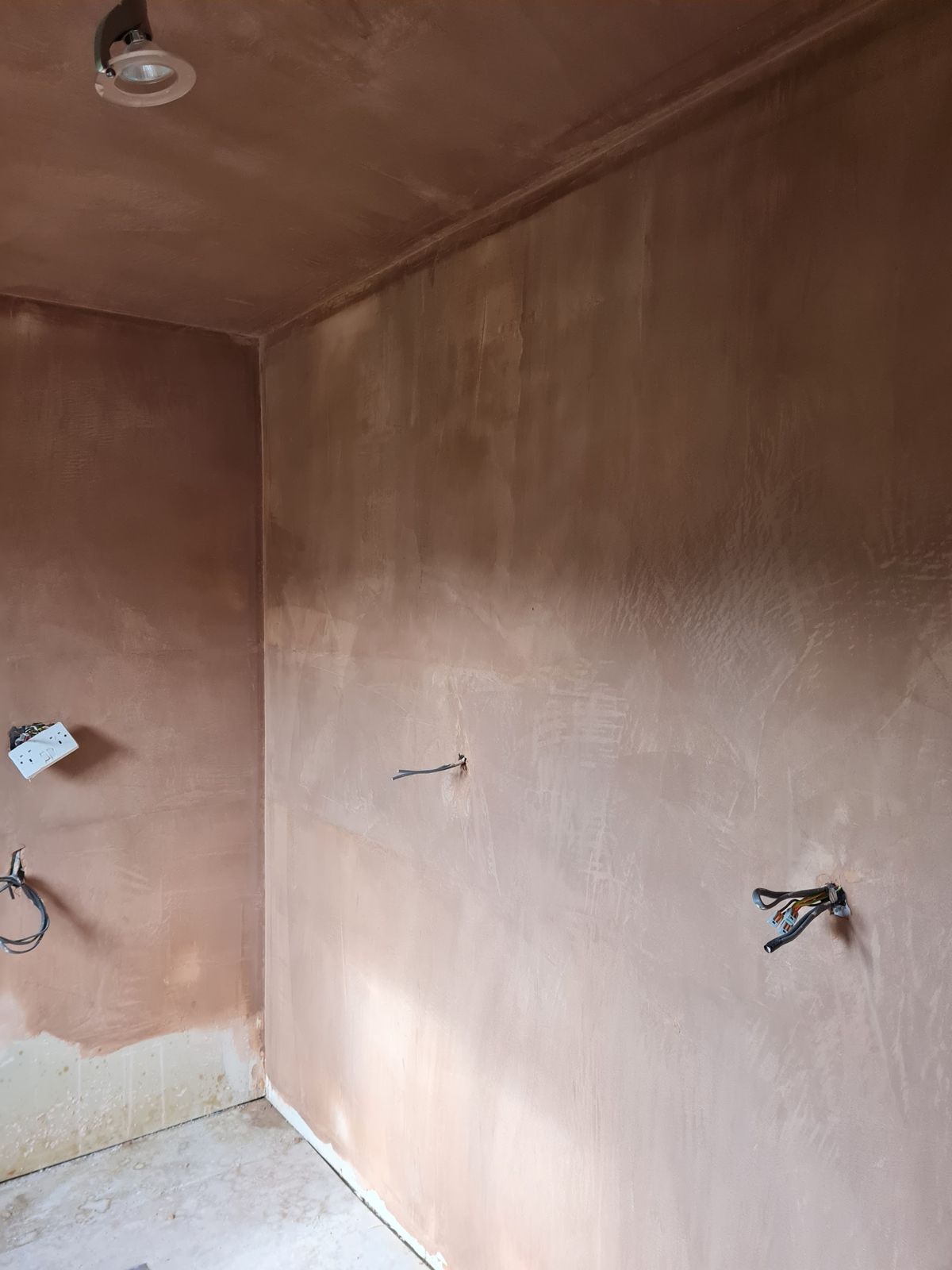 Freshly skimmed walls and ceiling with pink plaster drying